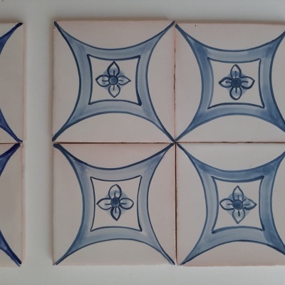 Azulejos cerâmicos brancos com padrão azul de losangos e flores estilizadas na parede