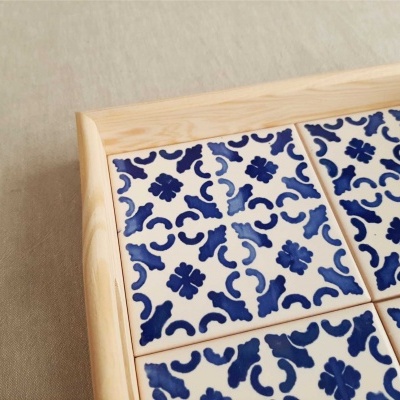 Azulejos cerâmicos azuis e brancos numa moldura de madeira sobre superfície cinza