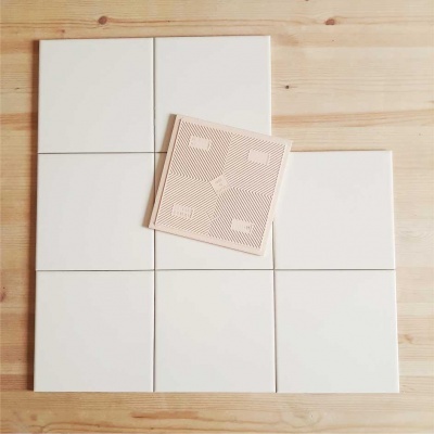 Azulejos brancos e um azulejo com padrão geométrico claro sobre madeira