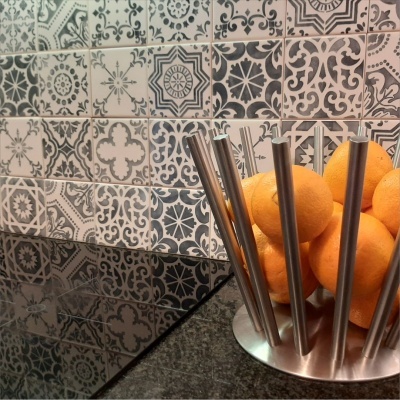 Fruteira metálica com laranjas na bancada com azulejos decorativos ao fundo