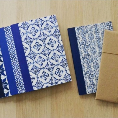 Três cadernos decorativos, dois em azul e branco e um embrulhado em papel castanho
