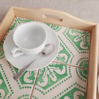 Bandeja de madeira clara com padrão verde e branco, chávena, prato e colher