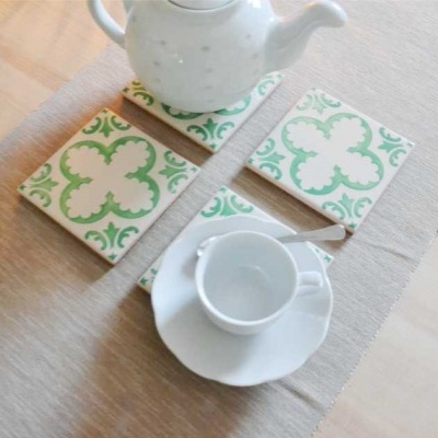 Bule, chávena e 3 tapetes sobre mesa de madeira clara