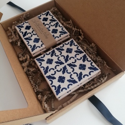 Conjunto de quatro azulejos decorativos com padrão azul em caixa de cartão