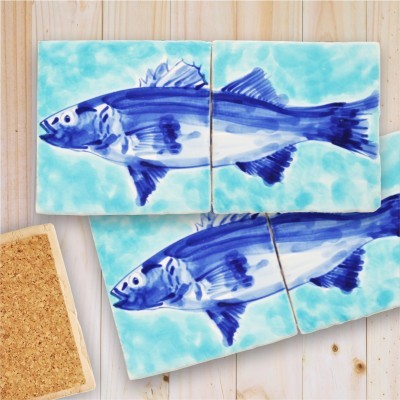 Azulejos de cerâmica azuis com desenho de peixe sobre mesa de madeira clara
