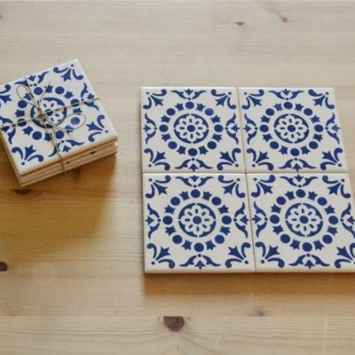 Conjunto de azulejos cerâmicos brancos com padrão azul sobre mesa de madeira clara