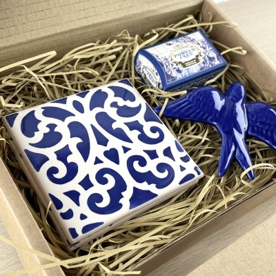 Gift box with ceramic tile, bird figurine, and small labeled box