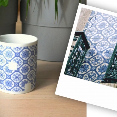 Caneca branca com padrões azuis e imagem polaroid de azulejos azuis na parede