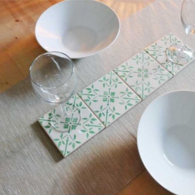 Mesa com duas tigelas brancas, dois copos e centro de mesa com azulejos brancos e verde