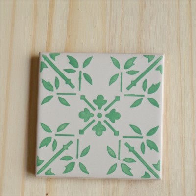 Azulejo cerâmico quadrado com padrão verde de folhas e elementos geométricos em fundo branco