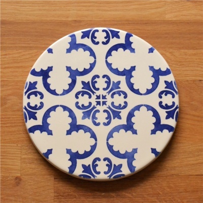 Prato redondo de cerâmica com padrão azul em fundo branco sobre madeira