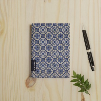 Caderno decorado azul e branco ao lado de caneta preta e planta