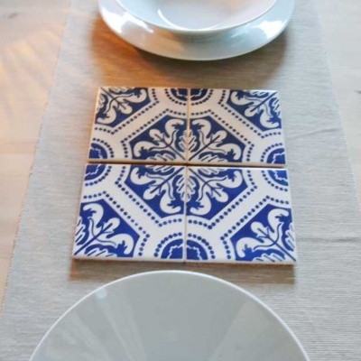 Azulejos azuis e brancos sobre pano cinzento numa mesa com pratos brancos