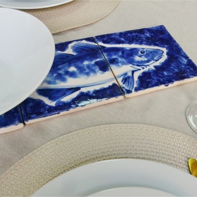 Azulejos decorativos com desenho de peixe azul numa mesa posta