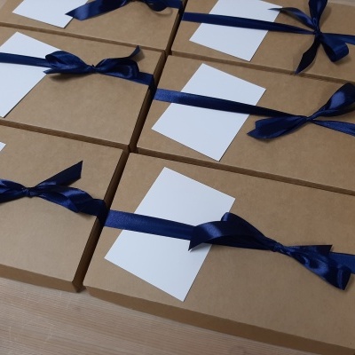 Caixas de papel castanho com laços azuis e cartões brancos em mesa de madeira