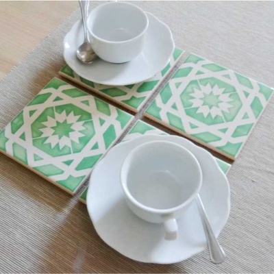 Conjunto de azulejos decorativos verdes com padrão geométrico com chávenas e pires brancos