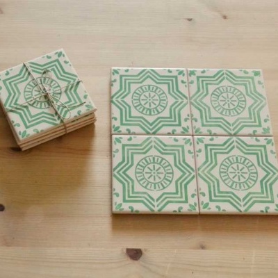 Azulejos quadrados com padrão verde sobre mesa de madeira clara