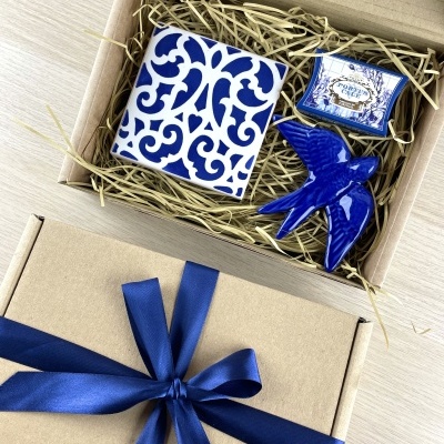 Gift box with blue patterned tile, blue ceramic bird, and PORTUS CALE labeled box in straw packing