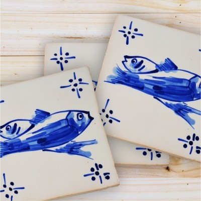 Azulejos de cerâmica branca com desenhos azuis de peixes e padrões decorativos sobre madeira clara