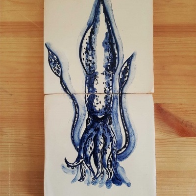 Azulejos decorativos quadrados com ilustração azul de lula em fundo branco sobre madeira