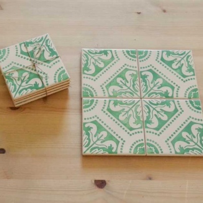 Azulejos cerâmicos quadrados com padrão verde e branco em superfície de madeira