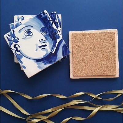 Azulejos de cerâmica pintados de azul com suporte de cortiça e fita dourada sobre fundo azul