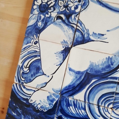 Painel de azulejos azuis e brancos com figura humana e flores