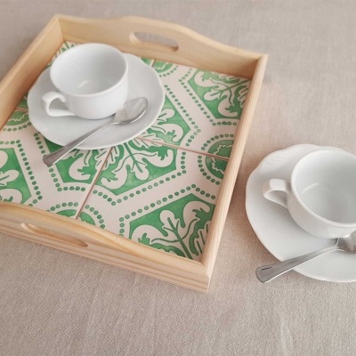 Tabuleiro de madeira com azulejos verdes e brancos, chávenas e colheres