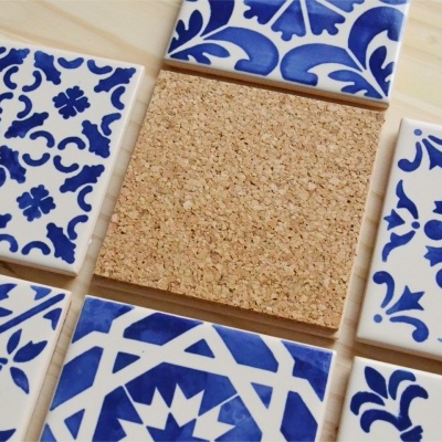 Azulejos quadrados azuis e brancos com um quadrado de cortiça no centro sobre madeira clara.