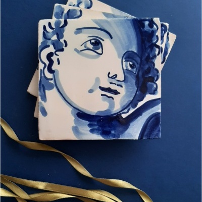 Azulejos pintados à mão com rosto de criança em azul e branco sobre fundo azul.