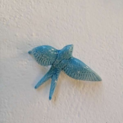 Figura decorativa de pássaro azul na parede branca