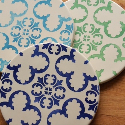 Três pratos redondos decorados com padrões florais coloridos sobre mesa de madeira