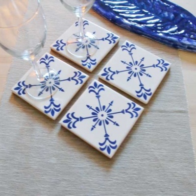 Azulejos de cerâmica branca com padrão azul sobre mesa com taças de vidro e travessa azul