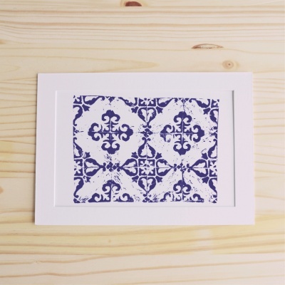 quadro com padrões azuis estilo azulejo português em fundo branco sobre mesa de madeira