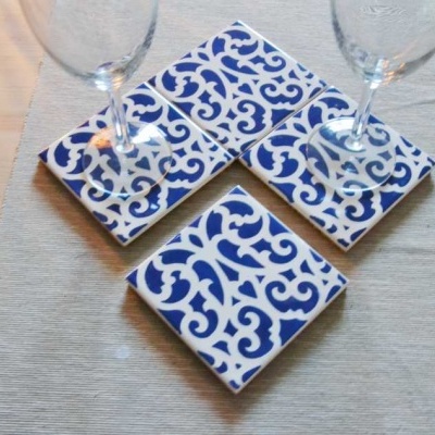 Três bases para copos quadradas em cerâmica com padrão azul e branco e dois copos de vidro