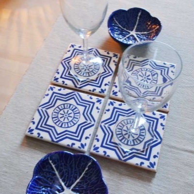 azulejos decorativos azuis e brancos com copos de vidro e pratos pequenos azuis sobre superfície clara