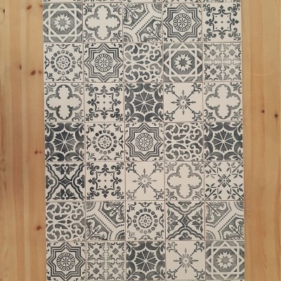 Tapete com padrão de azulejos cinza, branco e preto em chão de madeira