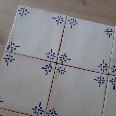 Azulejos brancos com padrão azul em cantos sobre madeira clara