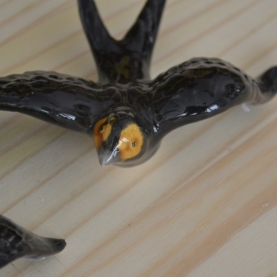 Pássaros decorativos em cerâmica preta e castanha sobre madeira clara