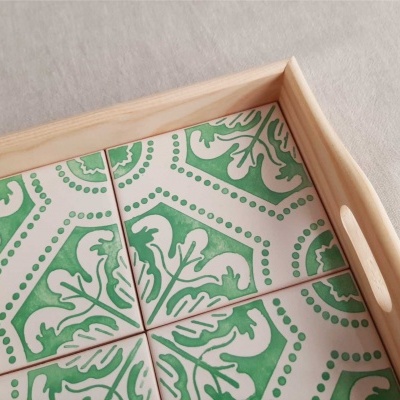 Tabuleiro de madeira com azulejos verdes e brancos com padrão floral