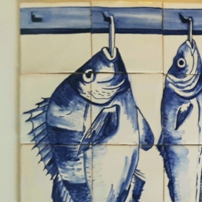Azulejos decorativos azuis e brancos com desenho de peixes pendurados