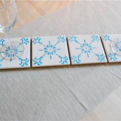 Bases quadradas de cerâmica branca com desenho azul e copos de vidro