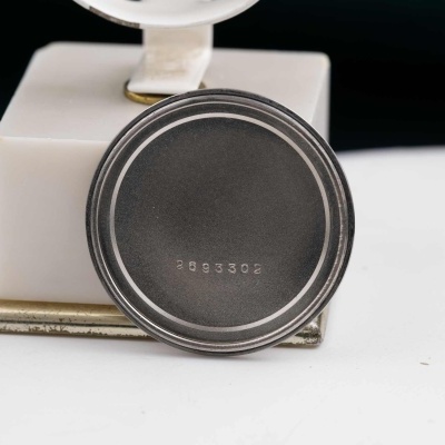 Parte posterior metálica redonda com número 3893302 sobre base quadrada branca