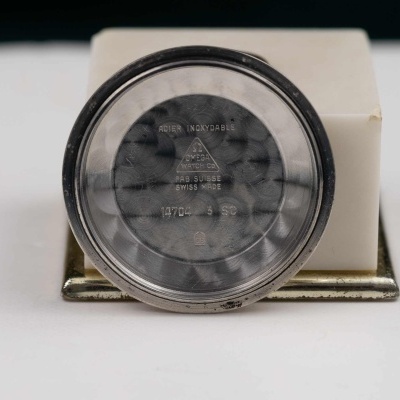 Mostrador redondo metálico de relógio com texto gravado e base branca