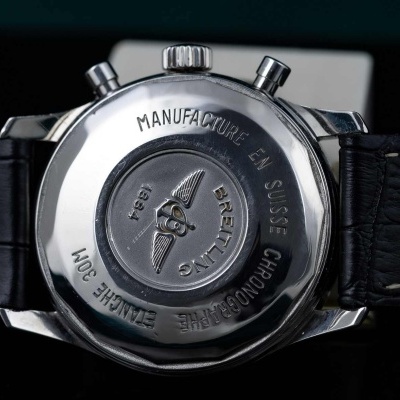 Verso de relógio de pulso em aço com bracelete preta em pele, gravações visíveis na parte de trás.