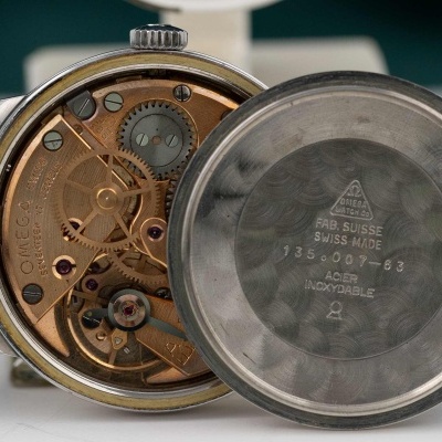 Relógio Omega com maquinaria visível e tampa em aço inoxidável inscrita.