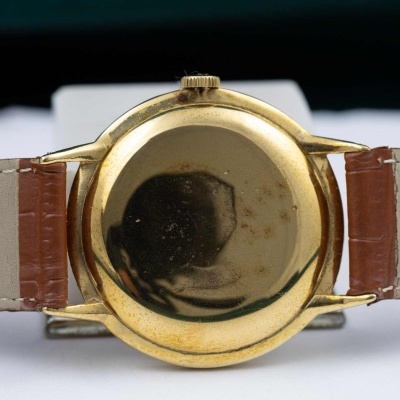 Relógio de pulso dourado com bracelete em pele bege e castanha visto de trás