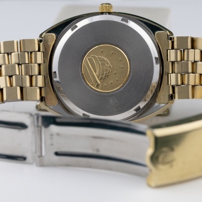 Relógio de pulso com bracelete metálica dourada e verso da caixa com emblema