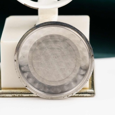 Relógio de pulso dourado de costas em cima de balança analógica branca