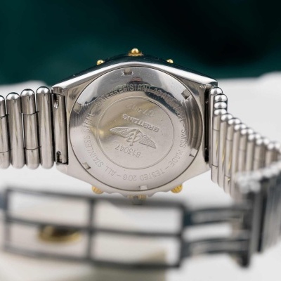 Parte traseira de relógio Breitling em metal prateado com inscrições e símbolo de asas